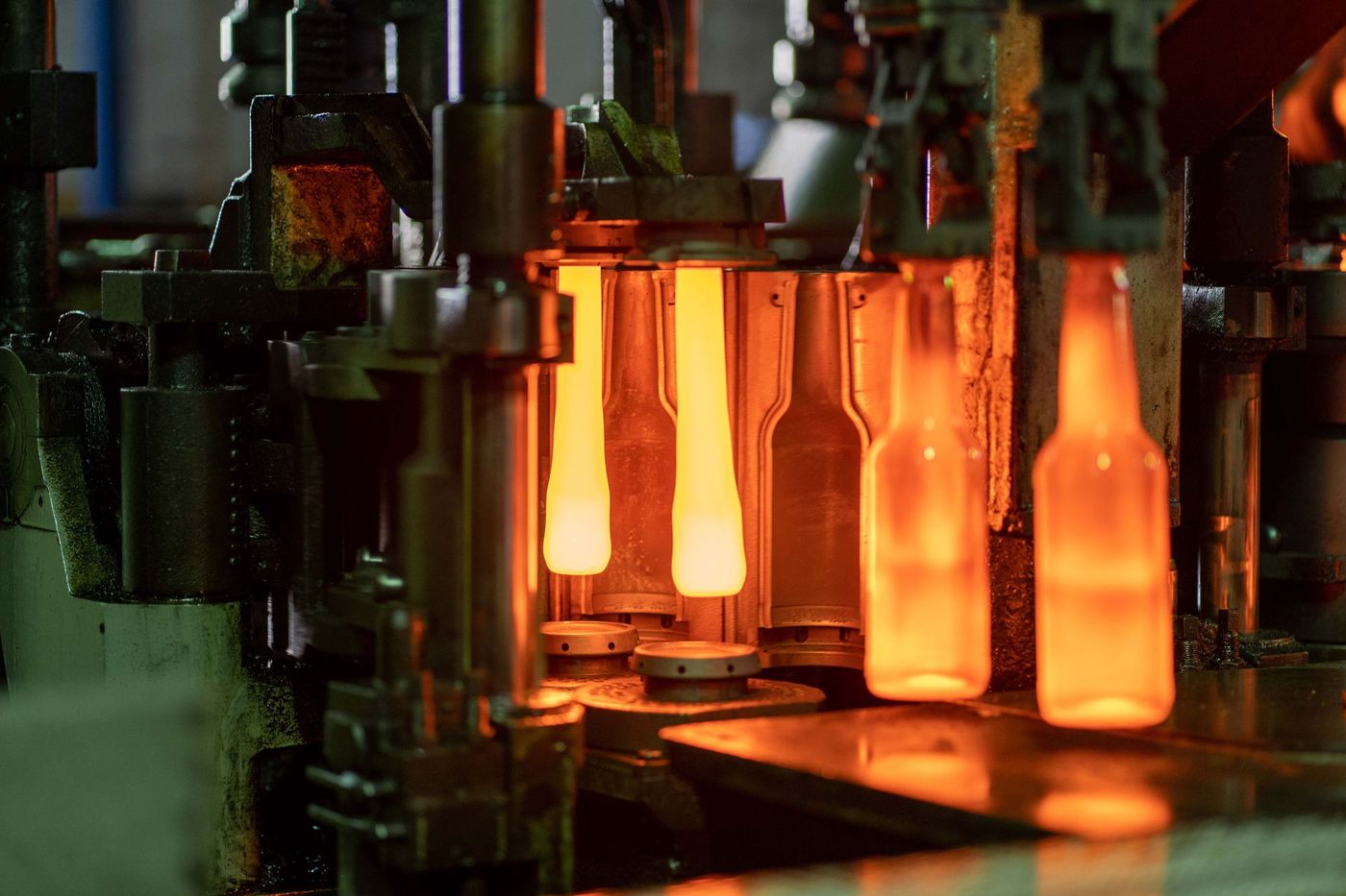 Glowing glass bottles leaving the forming machine