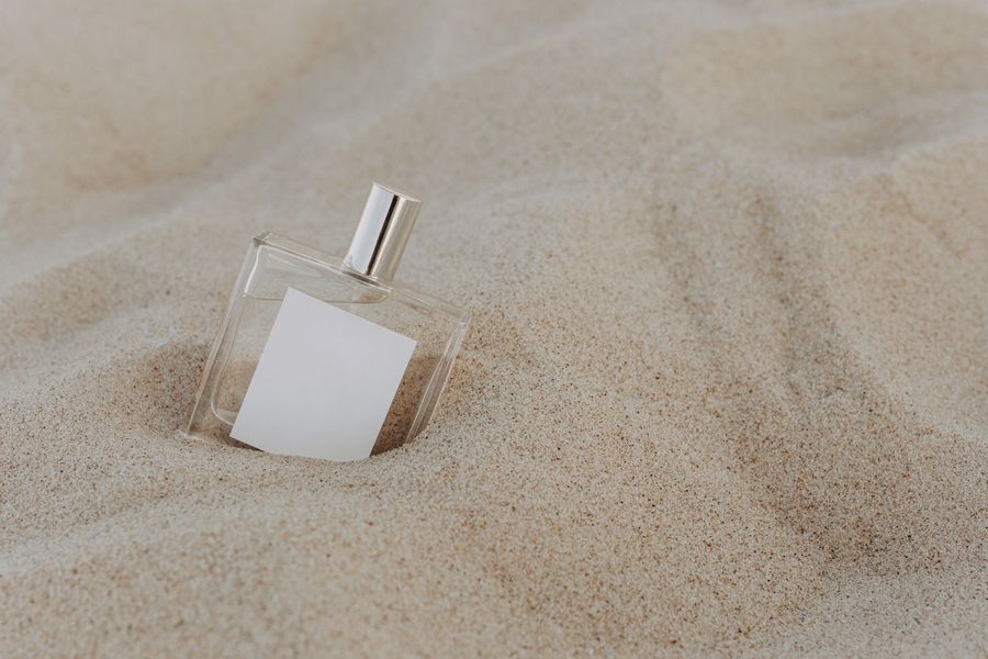 Clear square perfume bottle with blank label in sand